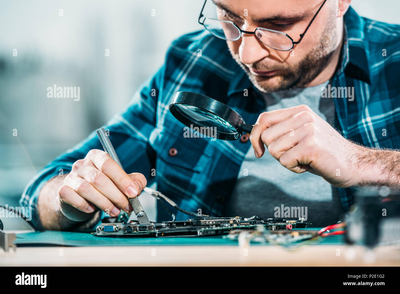 Engineer fixing circuit board looking through magnifying glass Stock ...