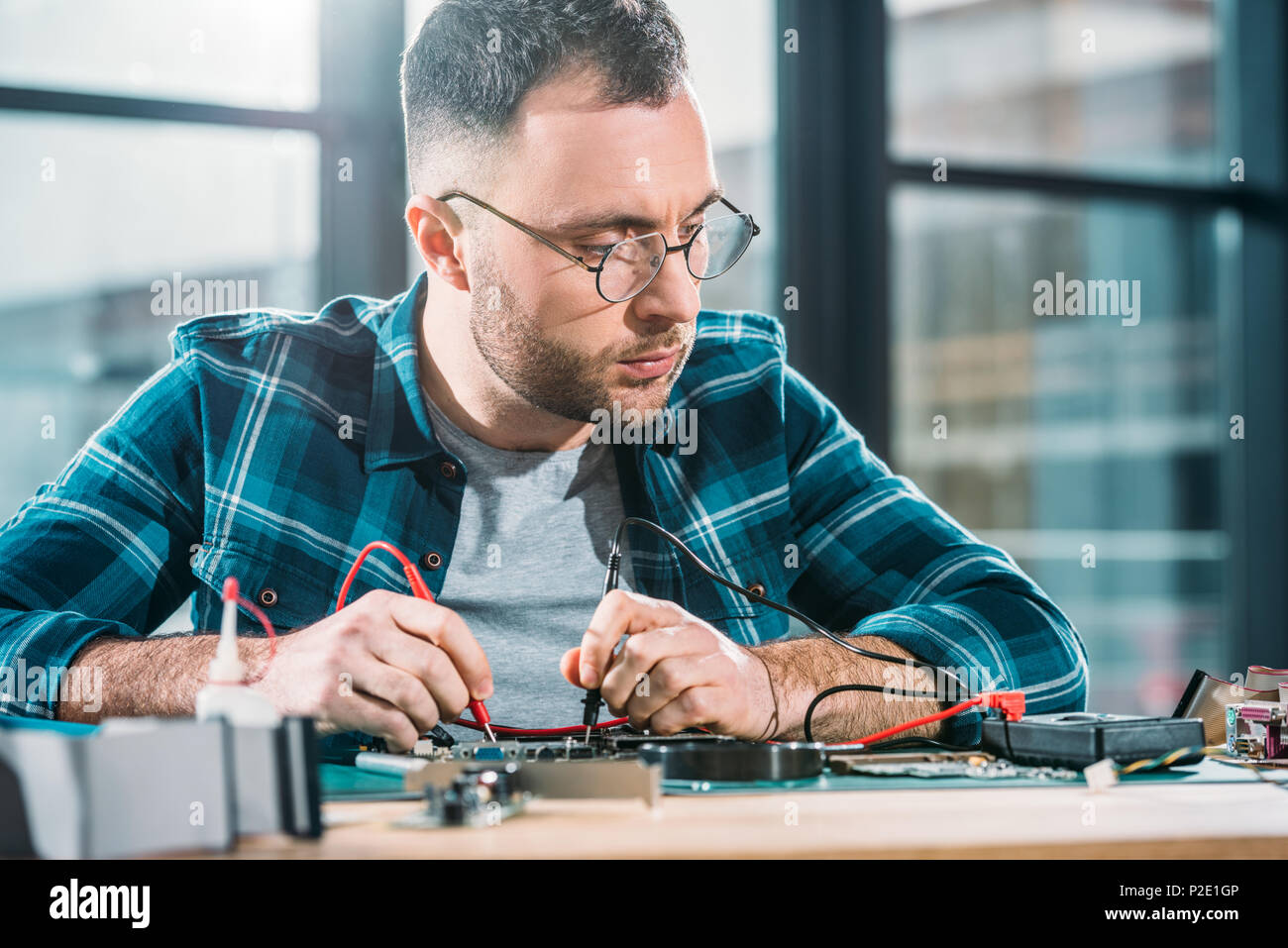 Repairman testing circuit board and checking multimeter measurements