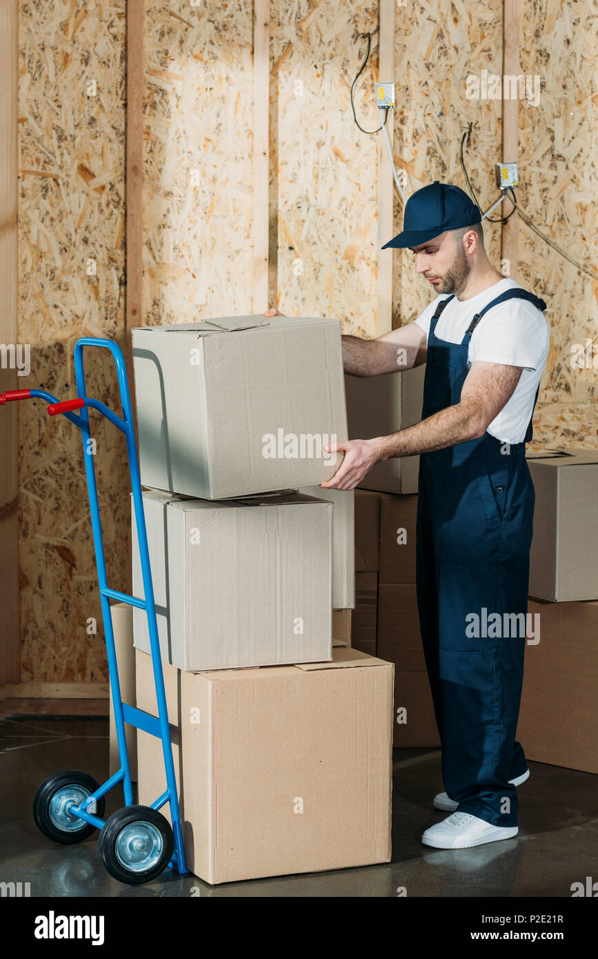 Loader man stacking cardboard boxes on cart Stock Photo