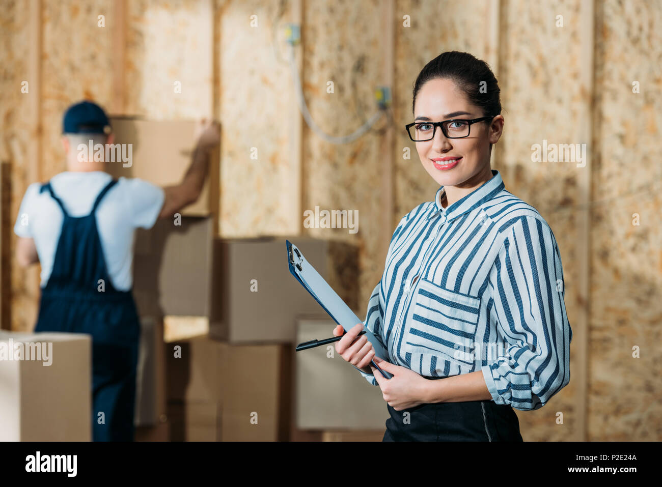 Smiling businesswoman holding cargo declaration standing near cargo boxes Stock Photo