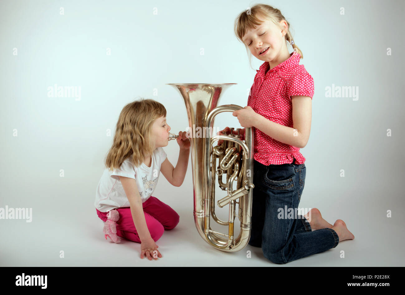 Young girl playing the euphonium whilst the other listens appreciatively Stock Photo