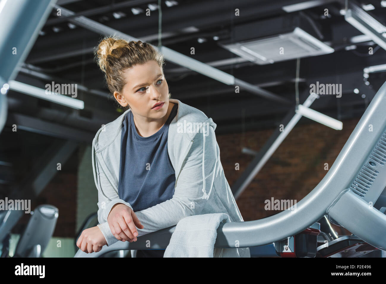 overweight woman leaning on rail of treadmill at gym Stock Photo