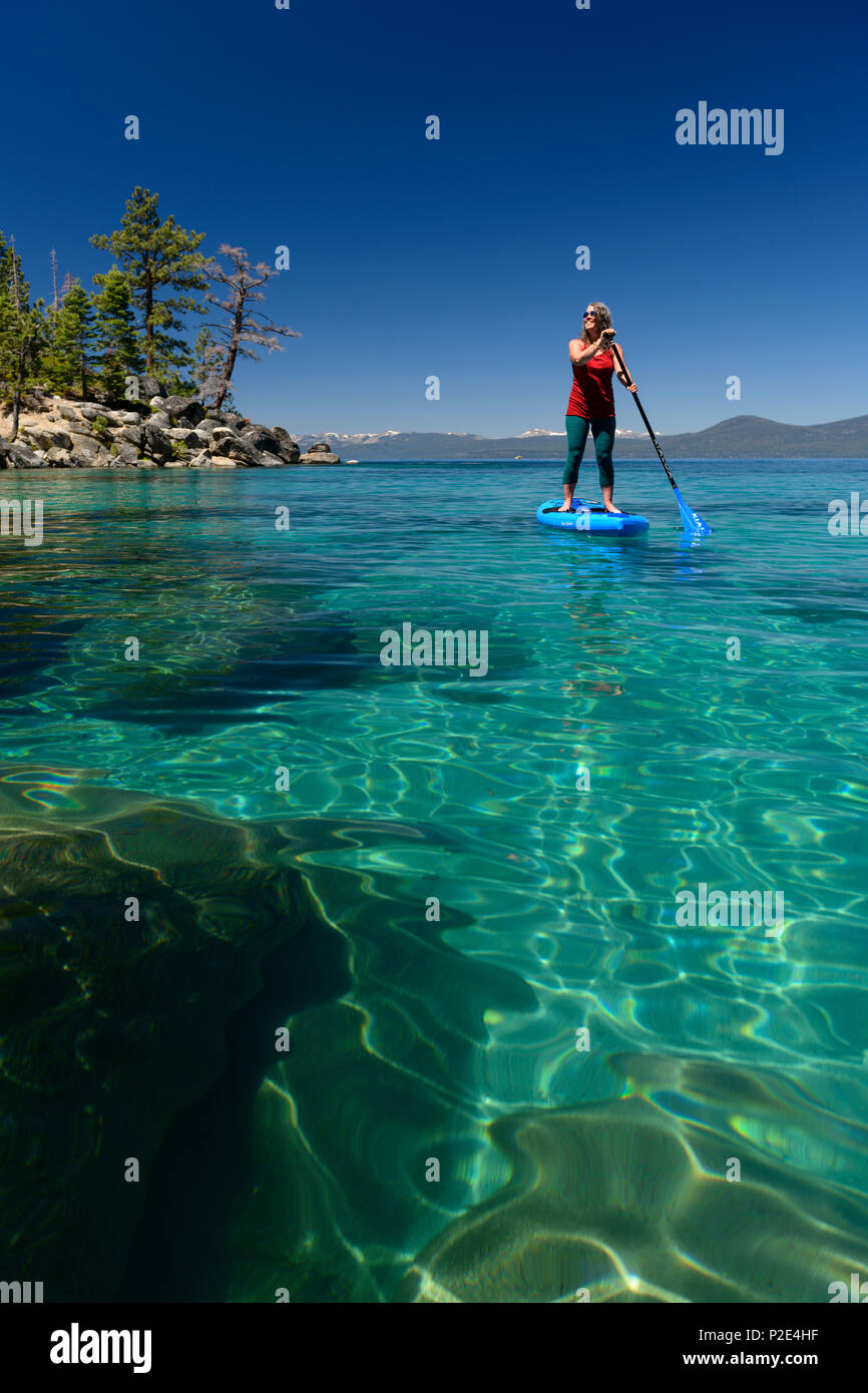 Woman stand up paddle boarding on the crystal clear blue waters of Lake Tahoe in Incline Village, Nevada, North America. Stock Photo
