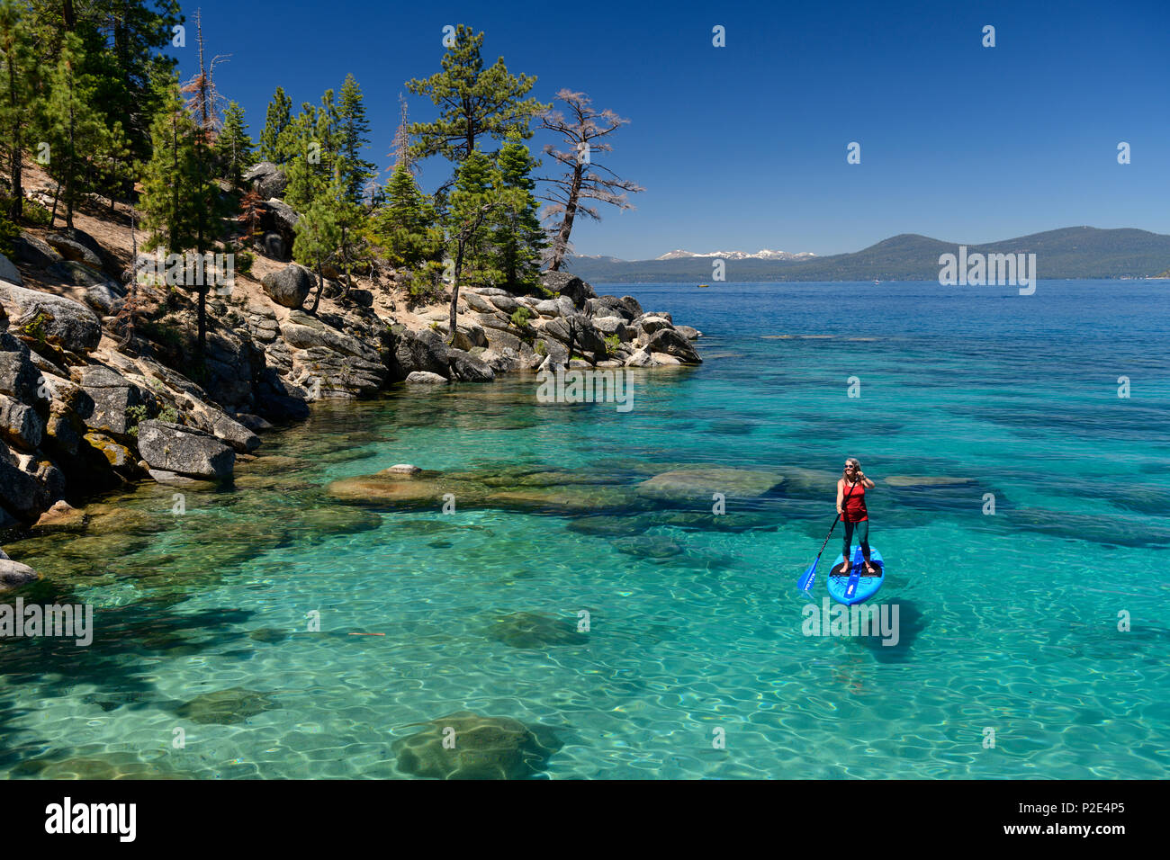 Woman stand up paddle boarding on the crystal clear blue waters of Lake