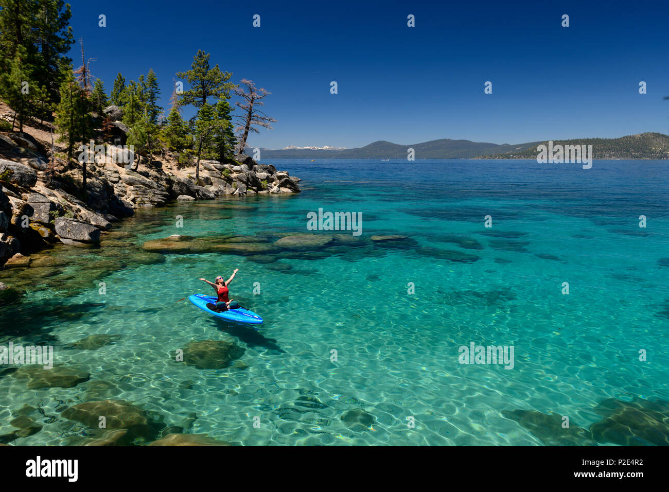 Woman stand up paddle boarding on the crystal clear blue waters of Lake