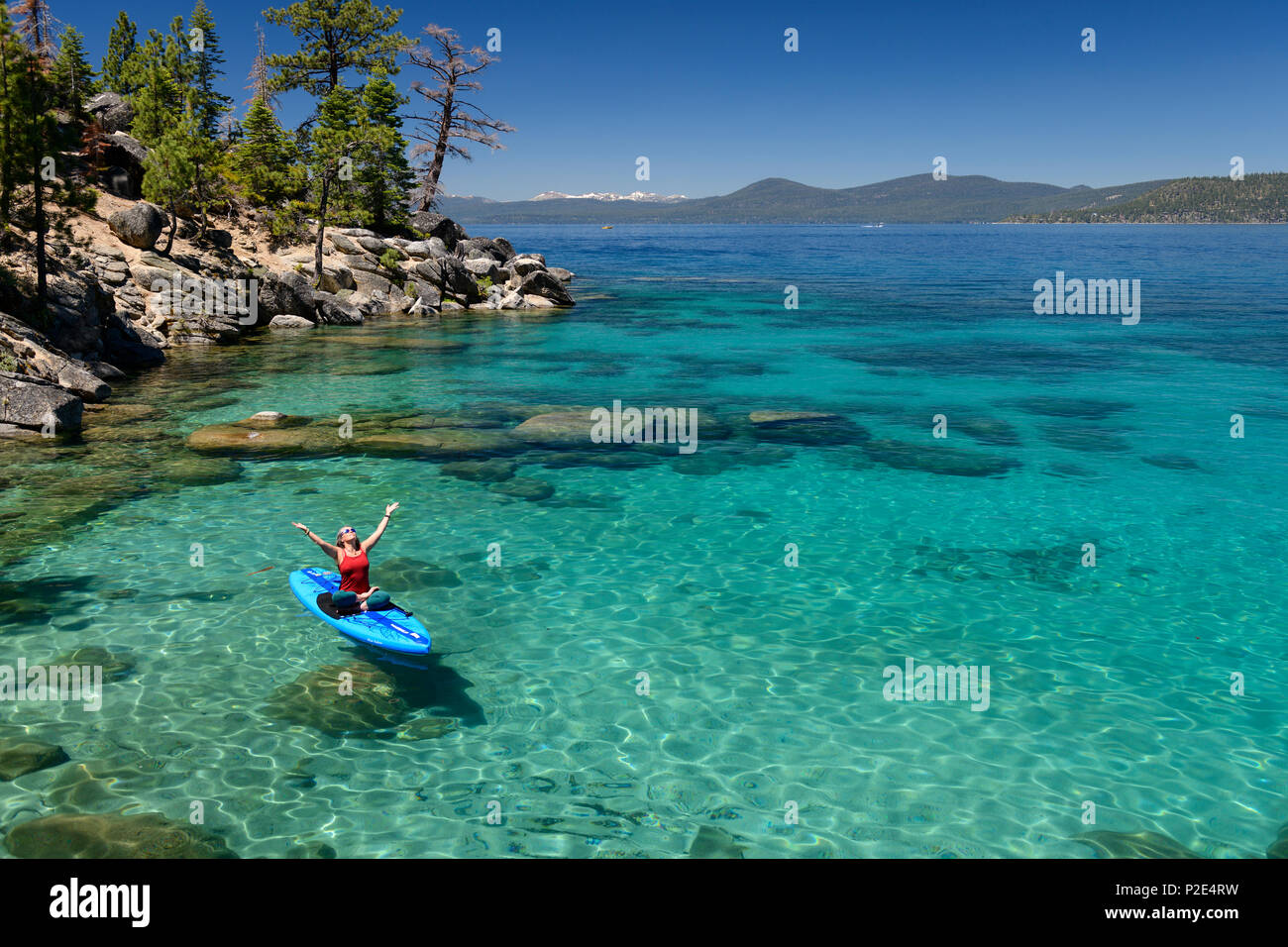 Woman stand up paddle boarding on the crystal clear blue waters of Lake Tahoe in Incline Village, Nevada, North America. Stock Photo