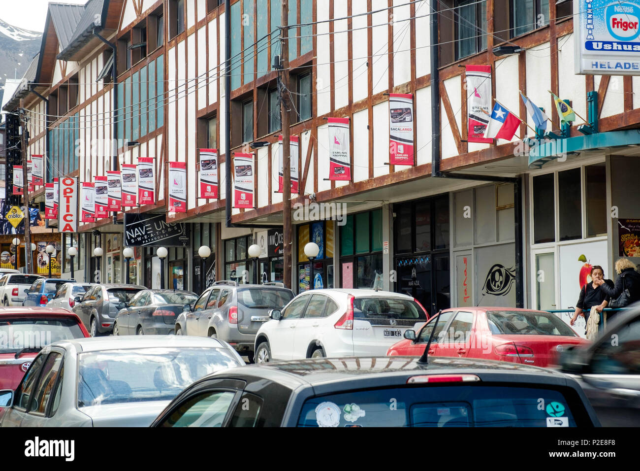 A shopping center borders a street in Ushuaia. The parking places are entirely occupied by cars. Stock Photo