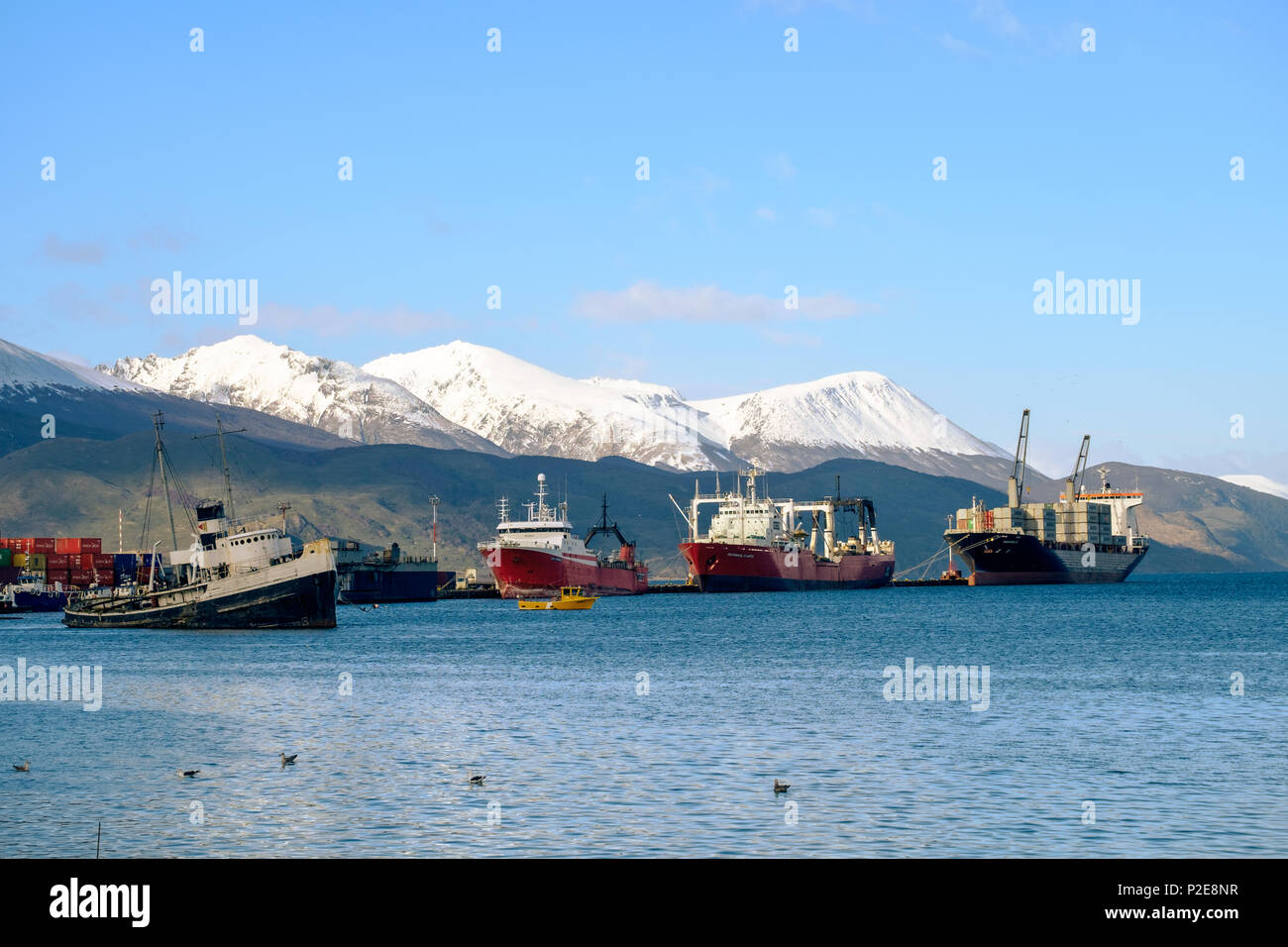The Saint-Christopher, an old boat, lies in the bay of Ushuaia. Behind that are a few container ships who show some small harbor activity. Stock Photo