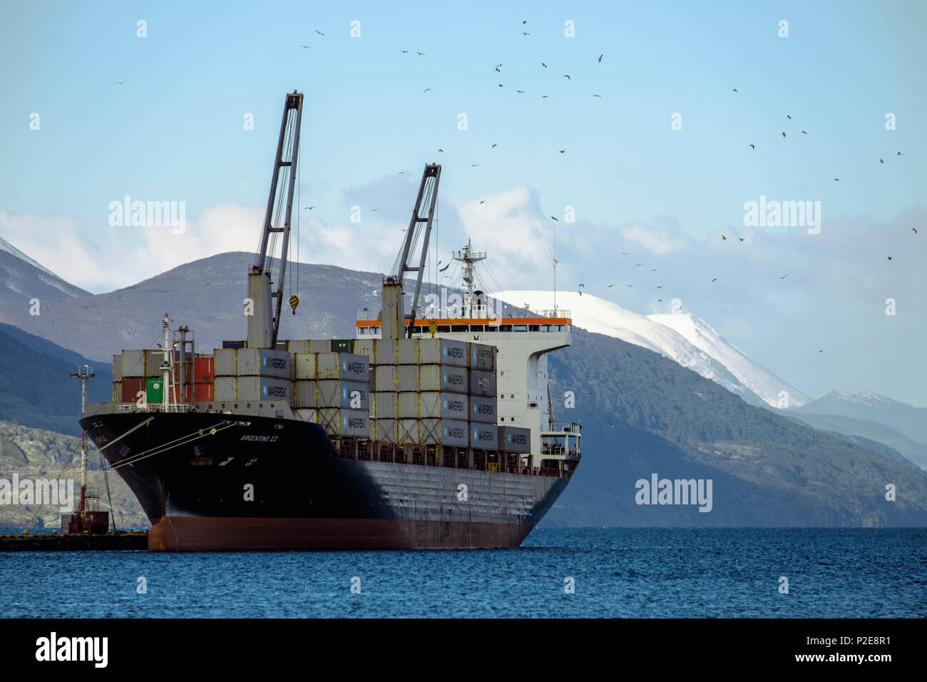 A large container ship lies in the small harbour of Ushuaia, in the south of Argentina. The Martial mountains are in the background. Stock Photo