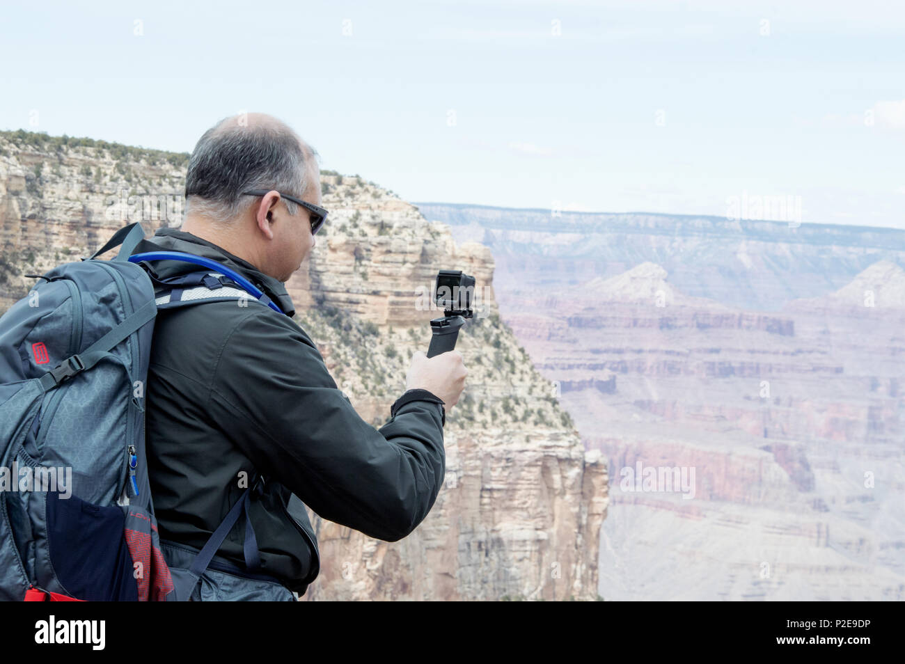 A man filming the Grand Canyon with a GoPro camera. Stock Photo