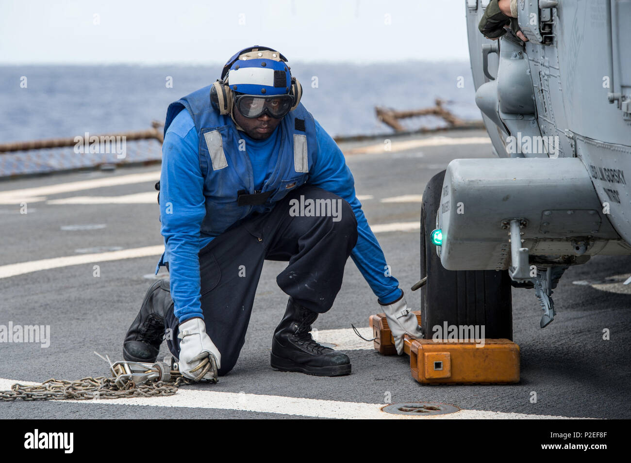 160913-N-UF697-090 PHILIPPINE SEA  (Sept. 13, 2016) Boatswain’s Mate 3rd Class Xavier Woods, assigned to the forward-deployed Arleigh Burke-class guided-missile destroyer USS Barry (DDG 52), prepares to remove chalks from a MH-60S Sea Hawk helicopter, assigned to the “Golden Falcons” of Helicopter Sea Combat Squadron (HSC) 12, after a refueling during Valiant Shield 2016. Valiant Shield is a biennial, U.S. only, field-training exercise with a focus on integration of joint training among U.S. forces. This is the sixth exercise in the Valiant Shield series that began in 2006. Barry is on patrol  Stock Photo