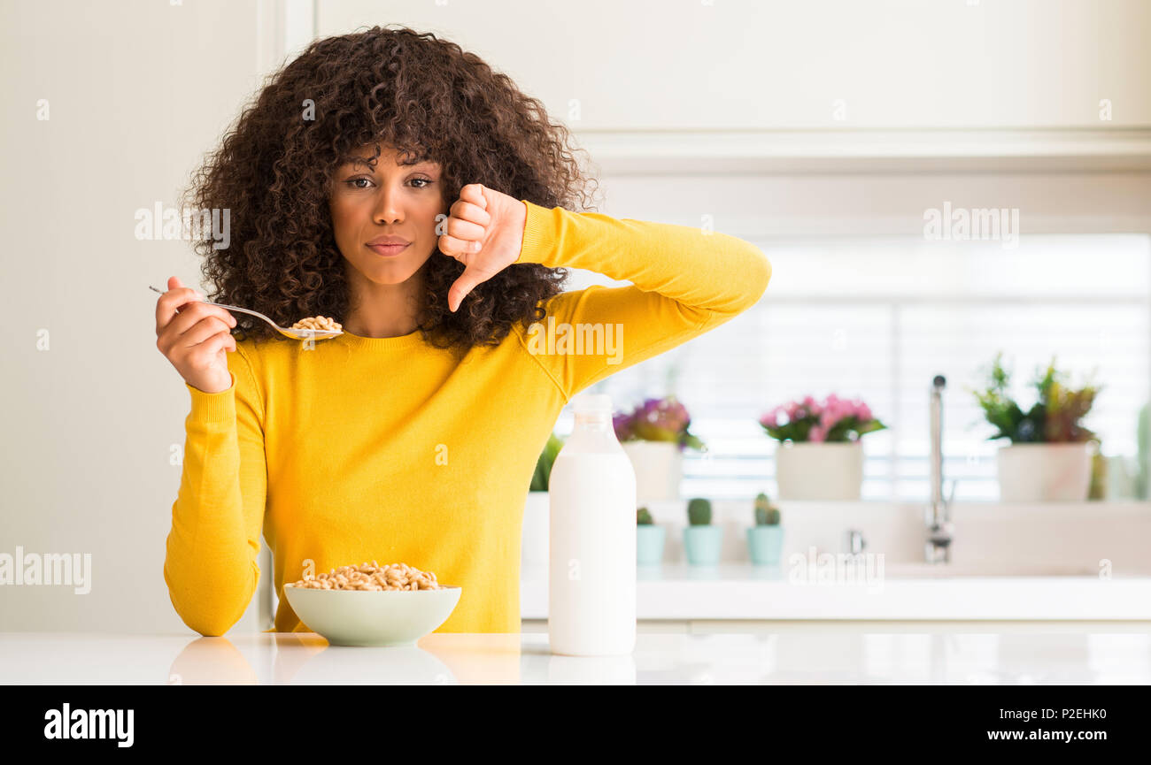 African american woman eating cereals and milk at home with angry face ...
