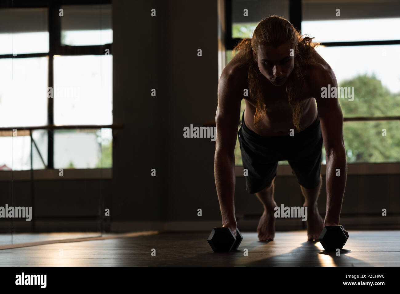 Man doing push-ups with dumbbells Stock Photo