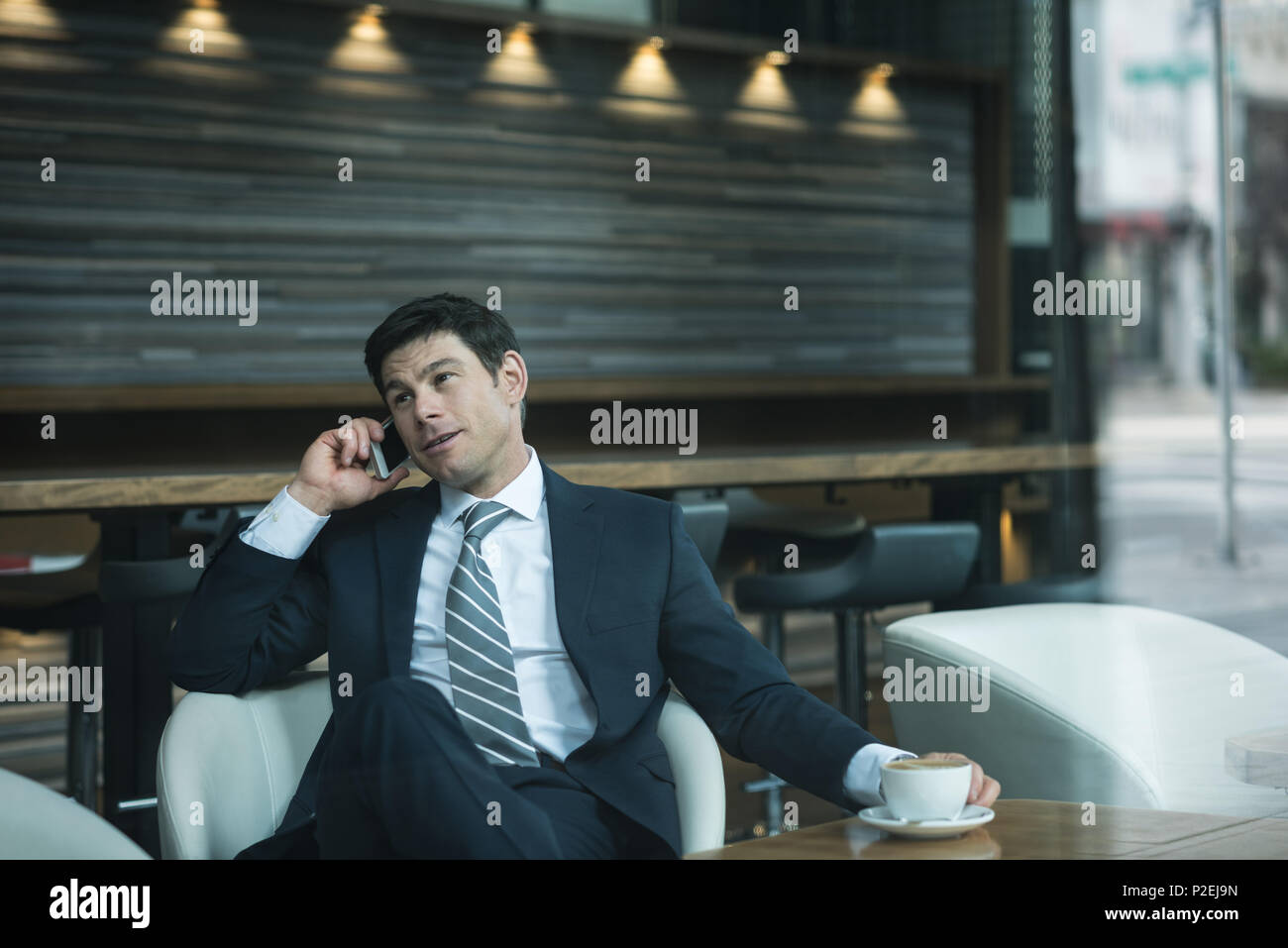 Businessman talking on phone while having coffee Stock Photo