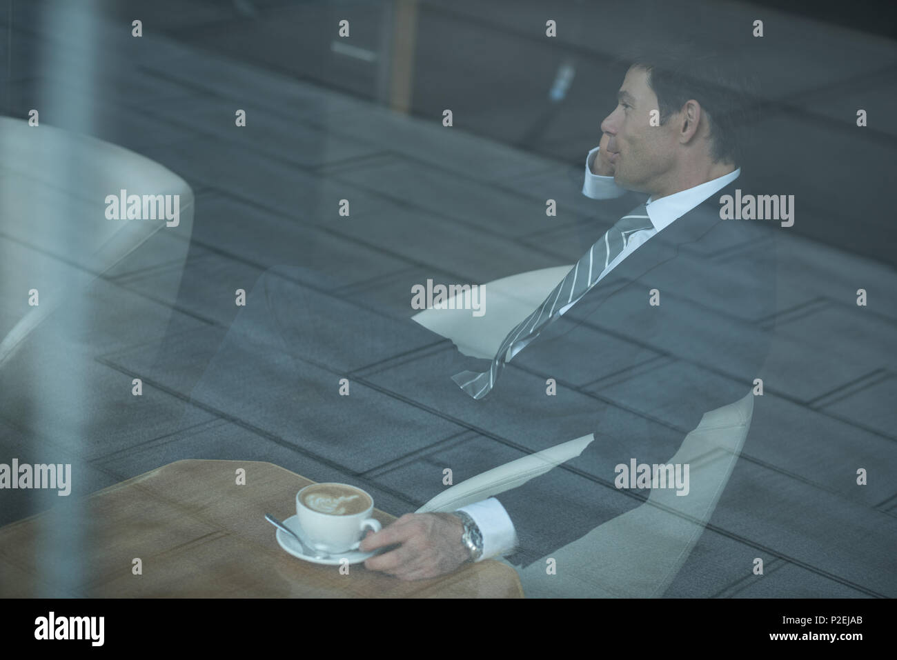 Businessman talking on mobile phone while having coffee Stock Photo
