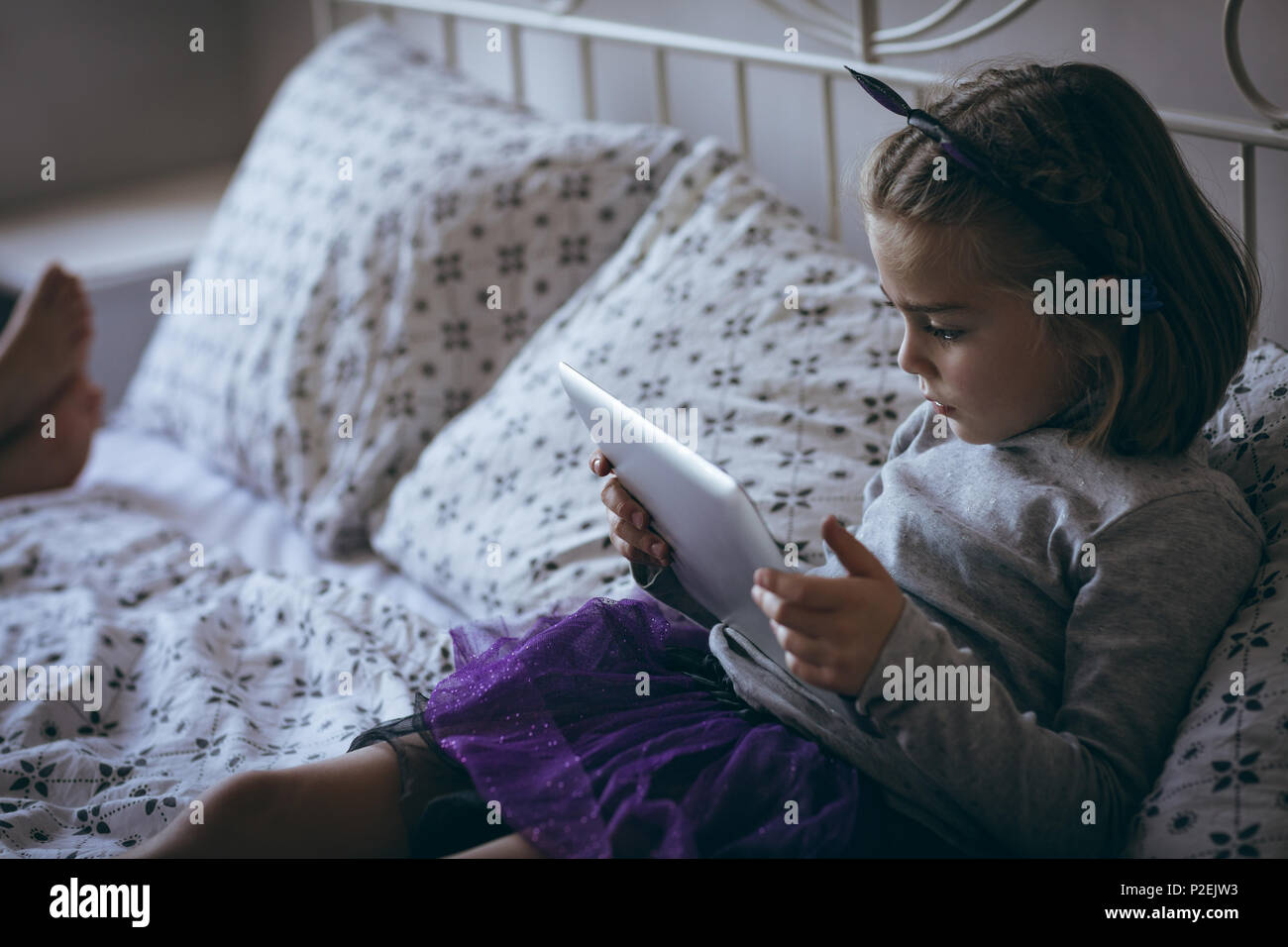 Girl using digital tablet on bed Stock Photo