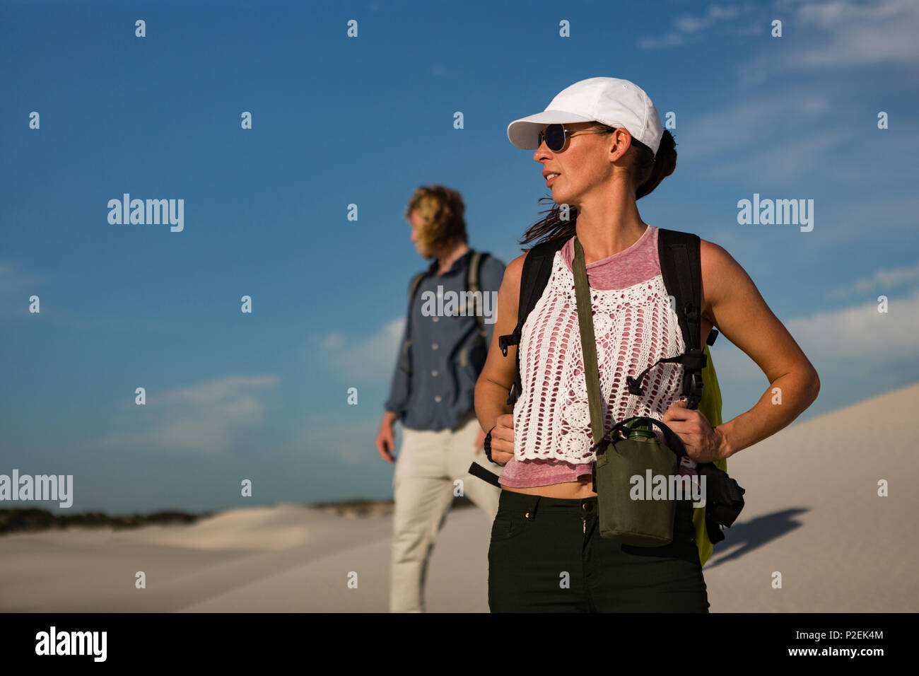 Couple with backpack standing on sand Stock Photo