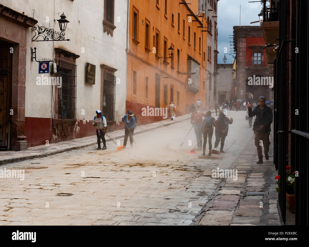 Young workers clean mud and dust off the streets of San Miguel de Allende, Mexico Stock Photo