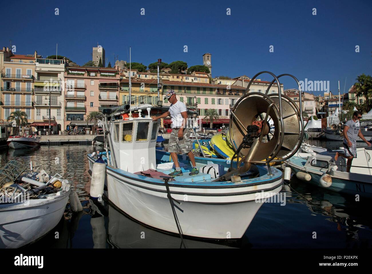 France, Alpes Maritimes, Cannes, Fisherman in his traditional fishboat in the Old port, with the district of the Suquet in the background Stock Photo