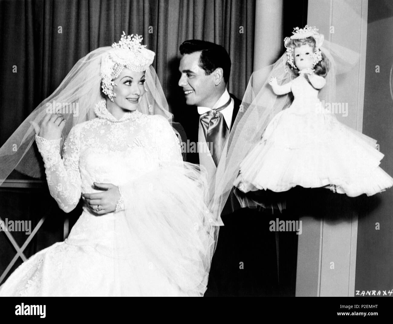 Description: Lucille Ball, vestidad de novia para iniciar la película 'Forever, Darling', posa en compañía de Desi Arnaz y de la muñeca que le regalaron los empleados de guardarropía y departamento de maquillaje el primer día de filmación..  Original Film Title: FOREVER, DARLING.  English Title: FOREVER, DARLING.  Film Director: ALEXANDER HALL.  Year: 1956.  Stars: LUCILLE BALL; DESI ARNAZ. Credit: M.G.M. / Album Stock Photo