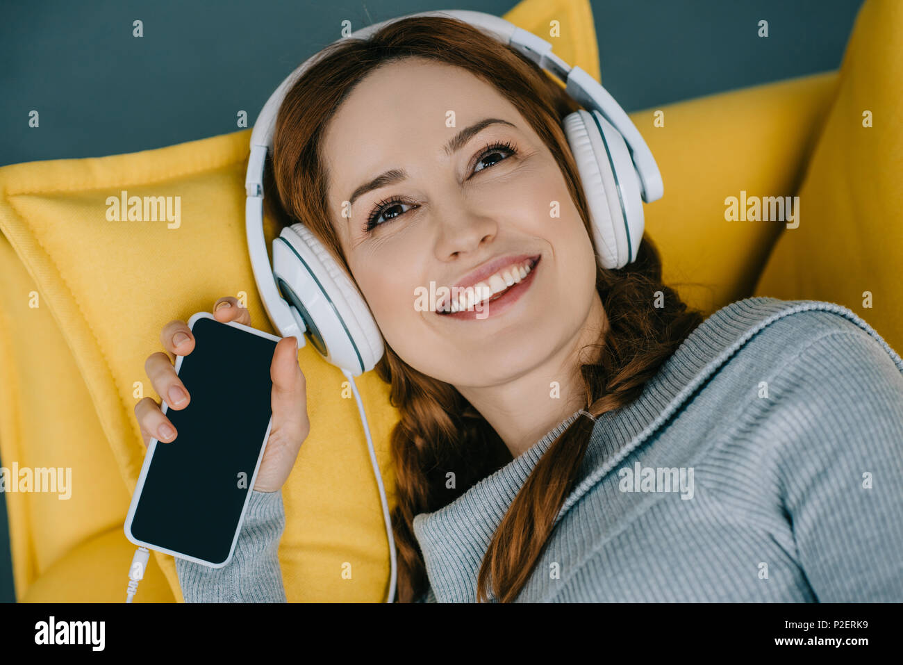 Happy woman lying on sofa and listening to music with smartphone Stock ...