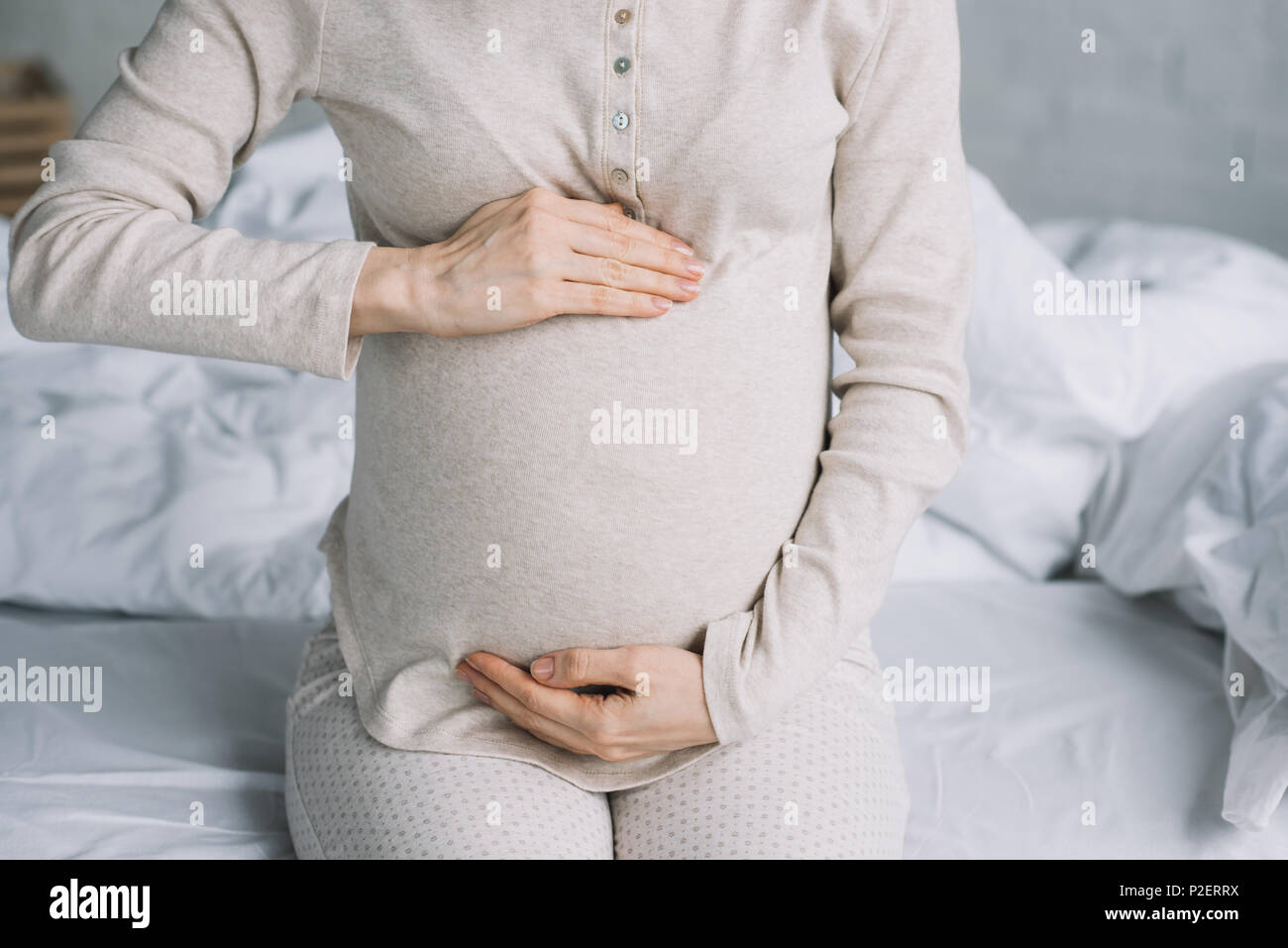 cropped image of pregnant woman touching belly in bedroom Stock Photo