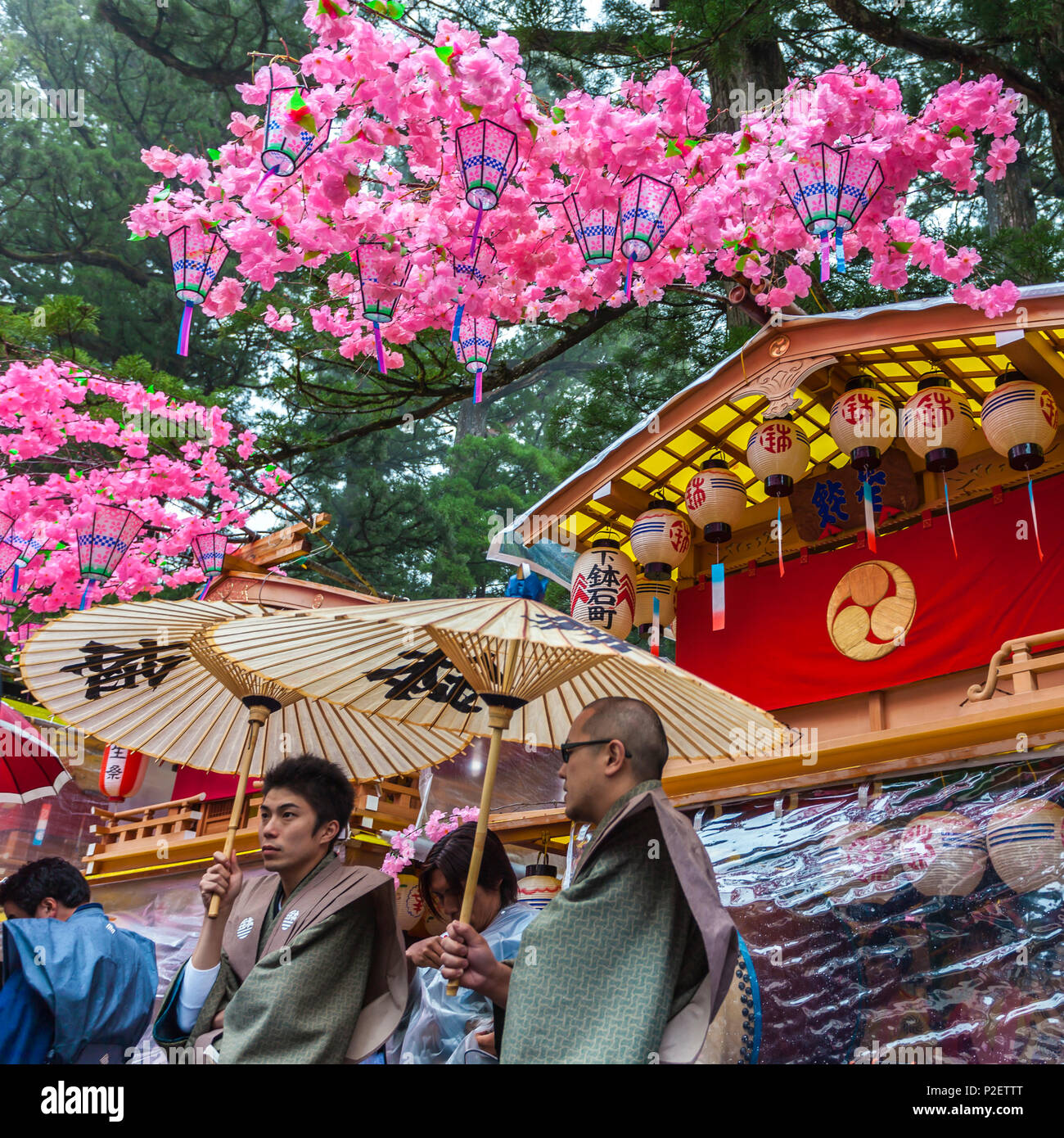 Two men with umbrellas in front of decorated festival wagon during Yayoi Matsuri in Nikko, Tochigi Prefecture, Japan Stock Photo