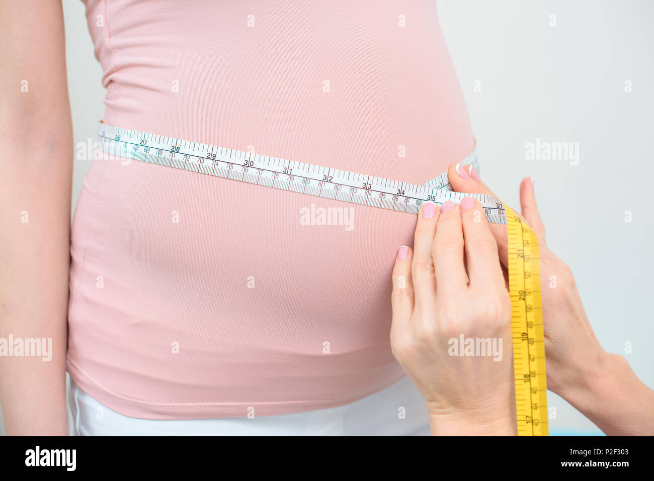cropped shot of obstetrician gynecologist measuring belly size of