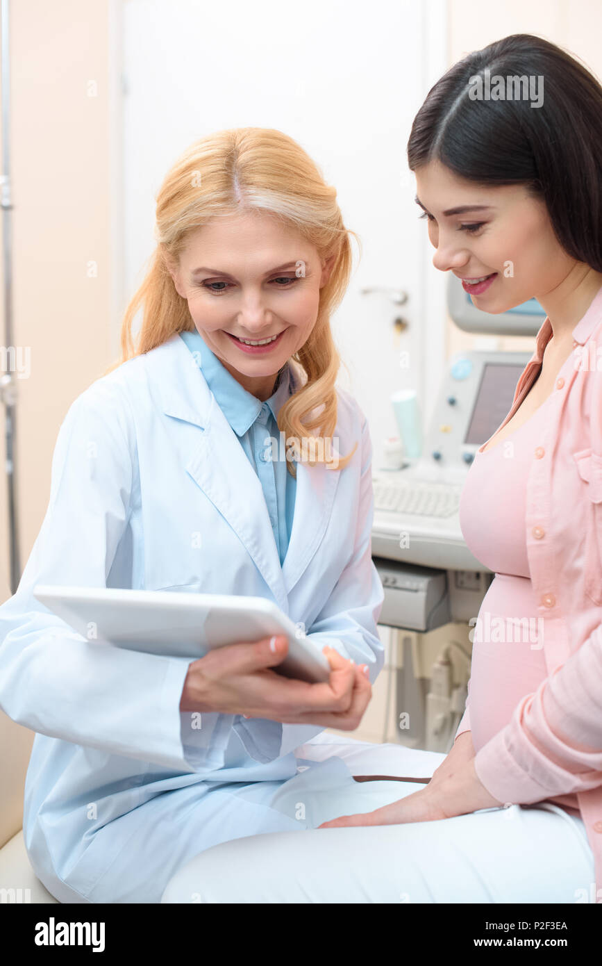 obstetrician gynecologist and pregnant woman using tablet together Stock Photo