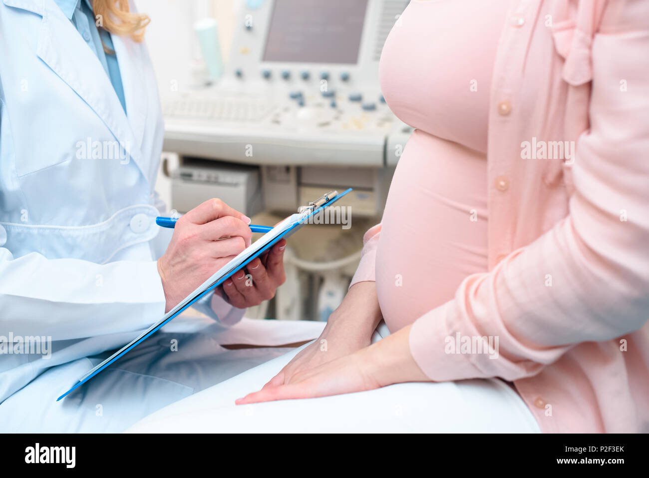 cropped shot of obstetrician gynecologist consulting pregnant woman and writing in clipboard Stock Photo