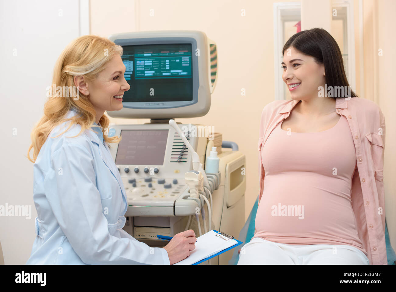 mature female obstetrician gynecologist consulting pregnant woman at ultrasound scanning office Stock Photo
