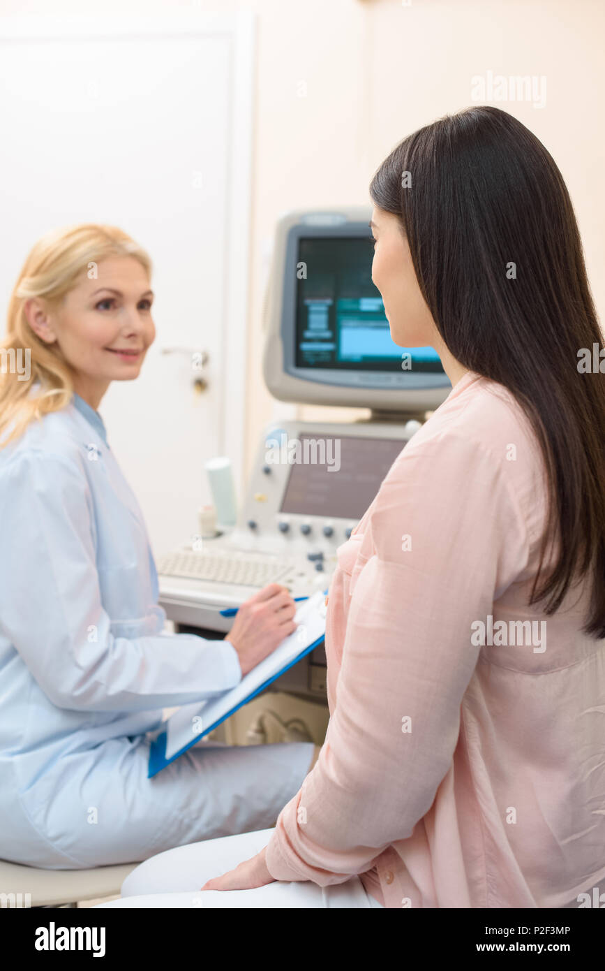 obstetrician gynecologist consulting pregnant woman at ultrasound scanning office Stock Photo