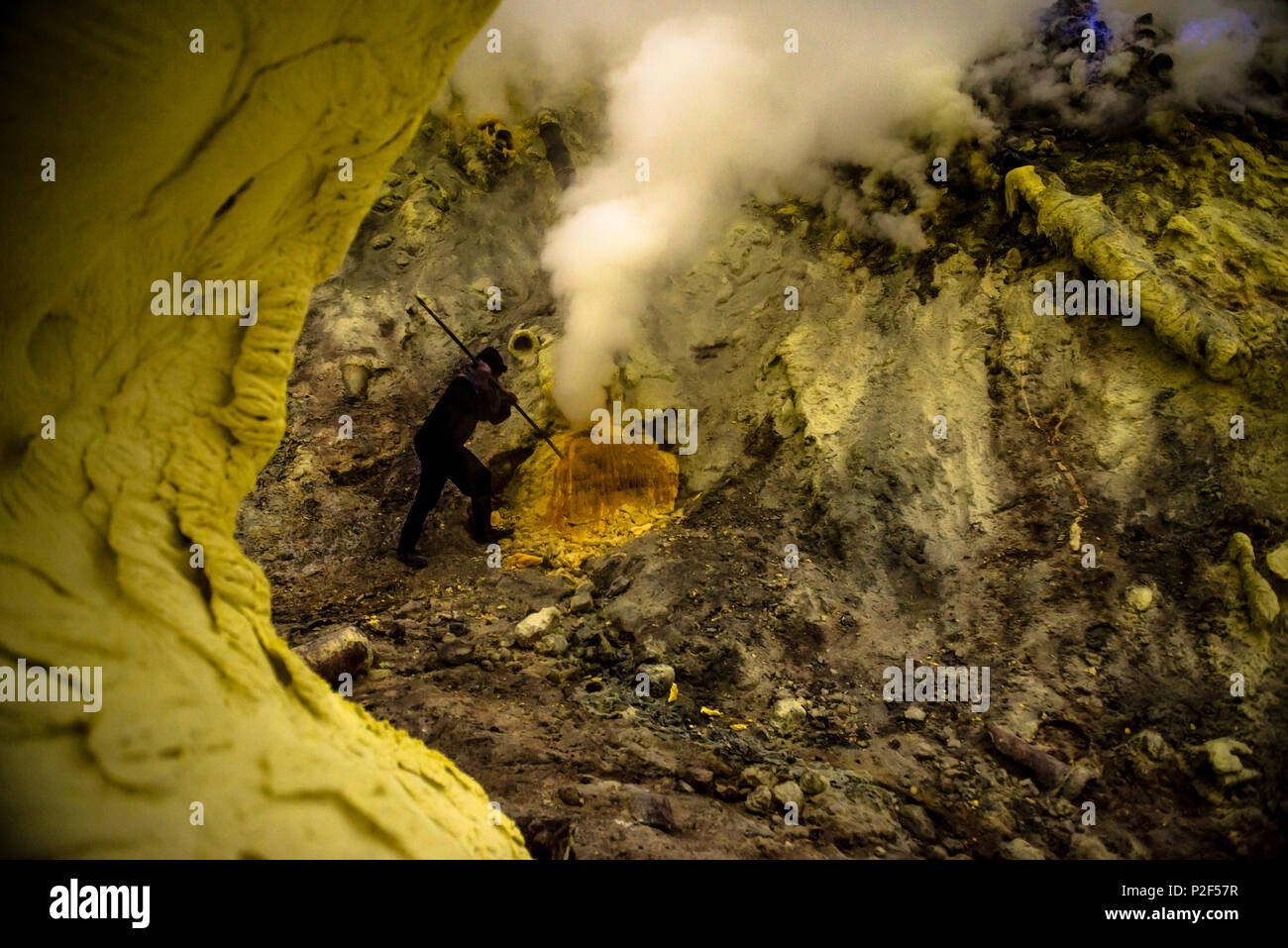 Miners with crowbars in the devil mine of Ijen volcano during sulfur mining - Indonesia, Java Stock Photo