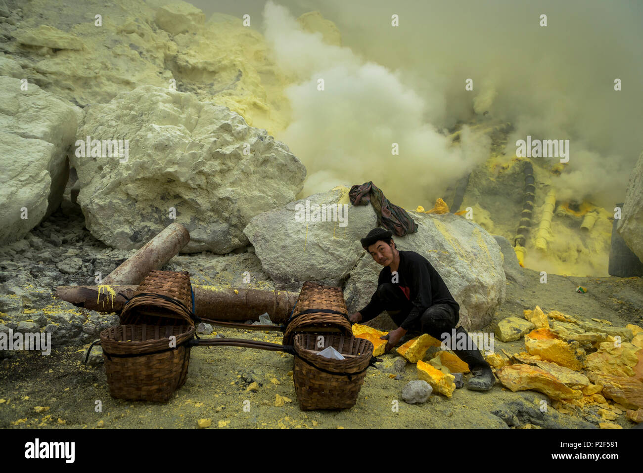 Miners of the devil mine of Ijen volcano loading transport baskets with sulfur - Indonesia, Java Stock Photo