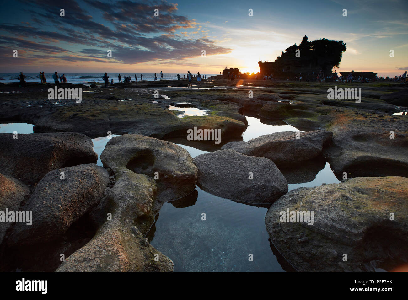 Visitors Tanah Lot, shore at low tide, in the evening, water temple Tanah Lot. Bali, Indonesia Stock Photo