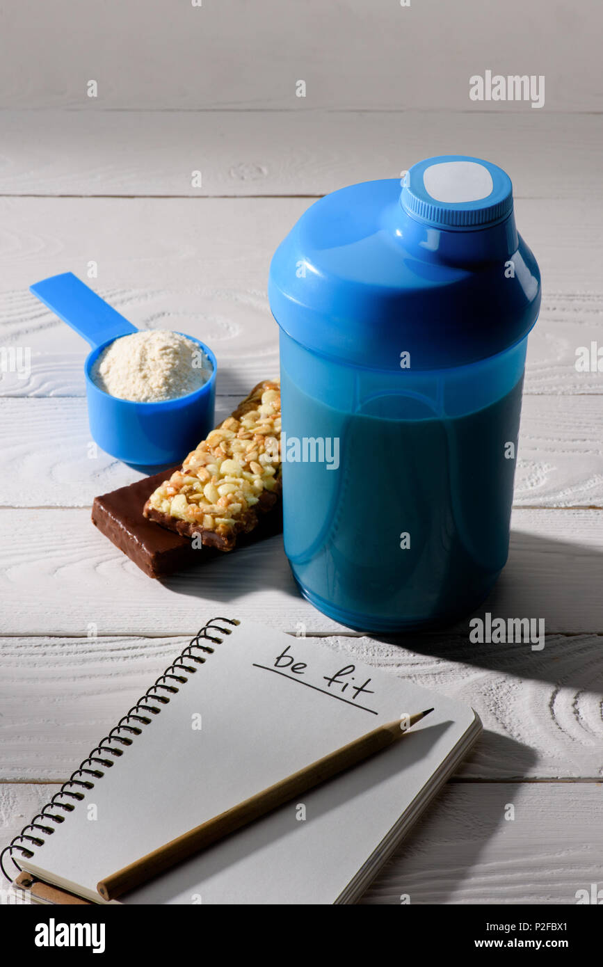 protein shaker with energy bars and measuring tape on white wooden table Stock Photo