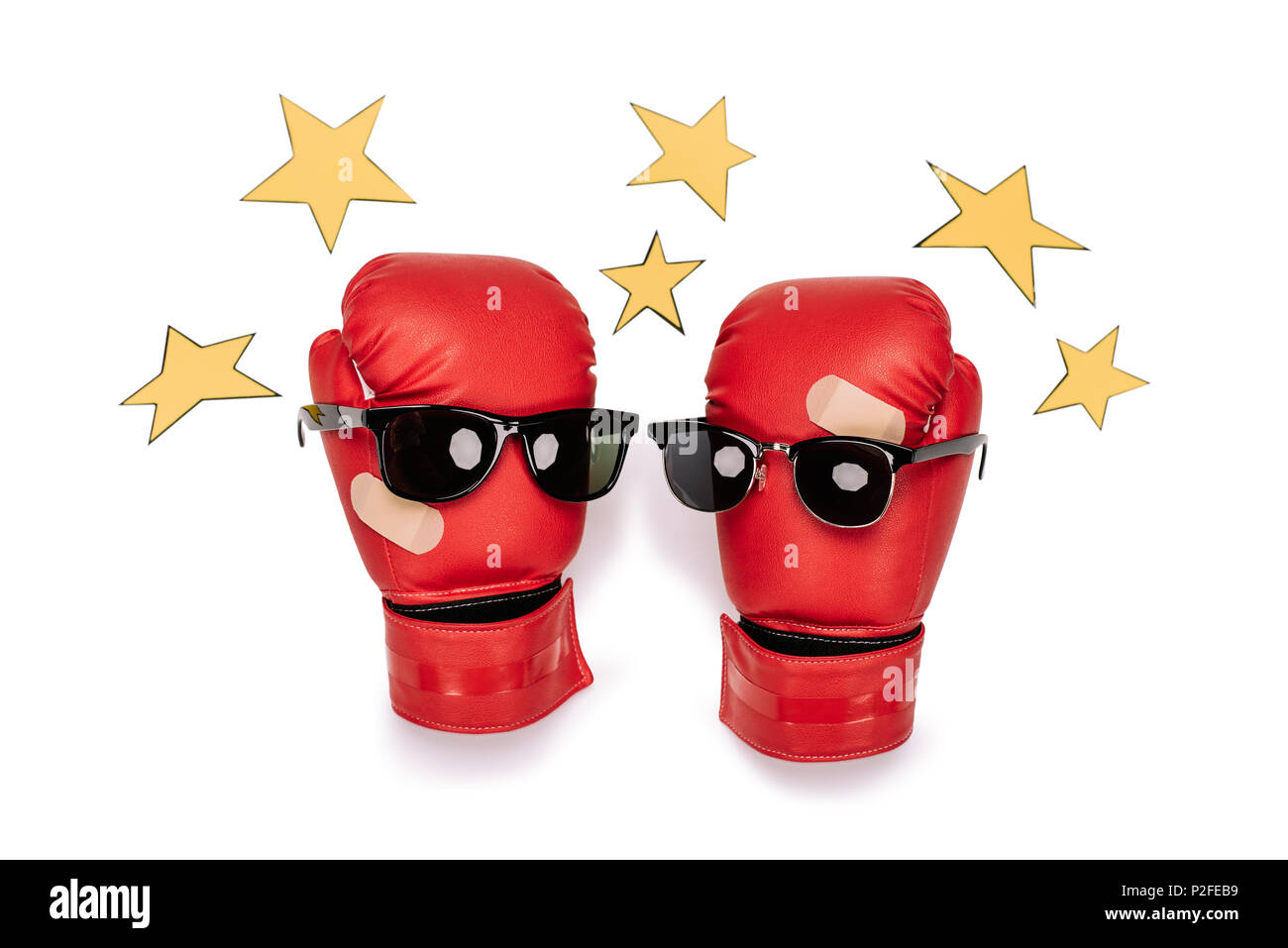 Pair of red boxing gloves in sunglasses making smiley composition with yellow stars around  isolated on white Stock Photo