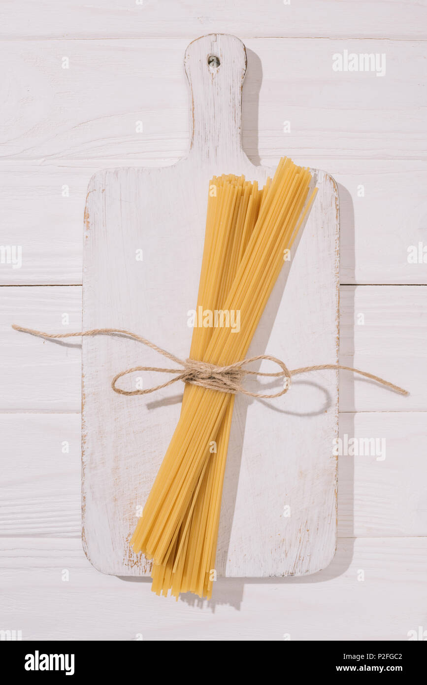 top view of spaghetti tied with thread lying on white wooden cutting ...