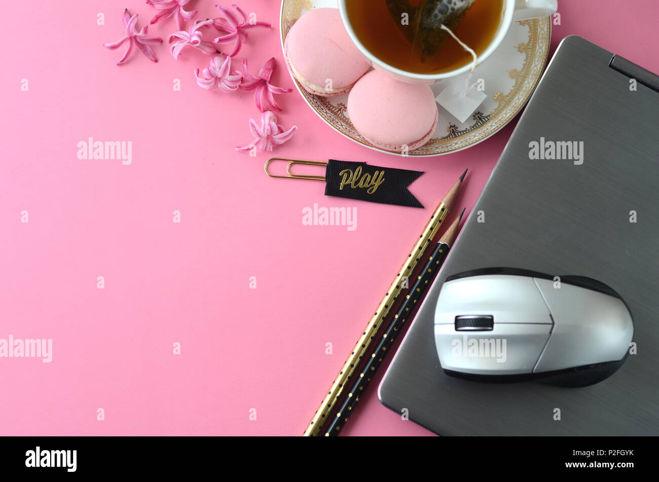 Top view flat layout of pink hyacinth, laptop, tea cup, French macarons on pink background. Feminine workspace. Working from home, freelancing concept Stock Photo