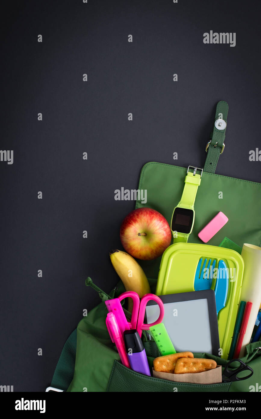 Backpack with school supplies on black background. Top view Flat lay Stock Photo