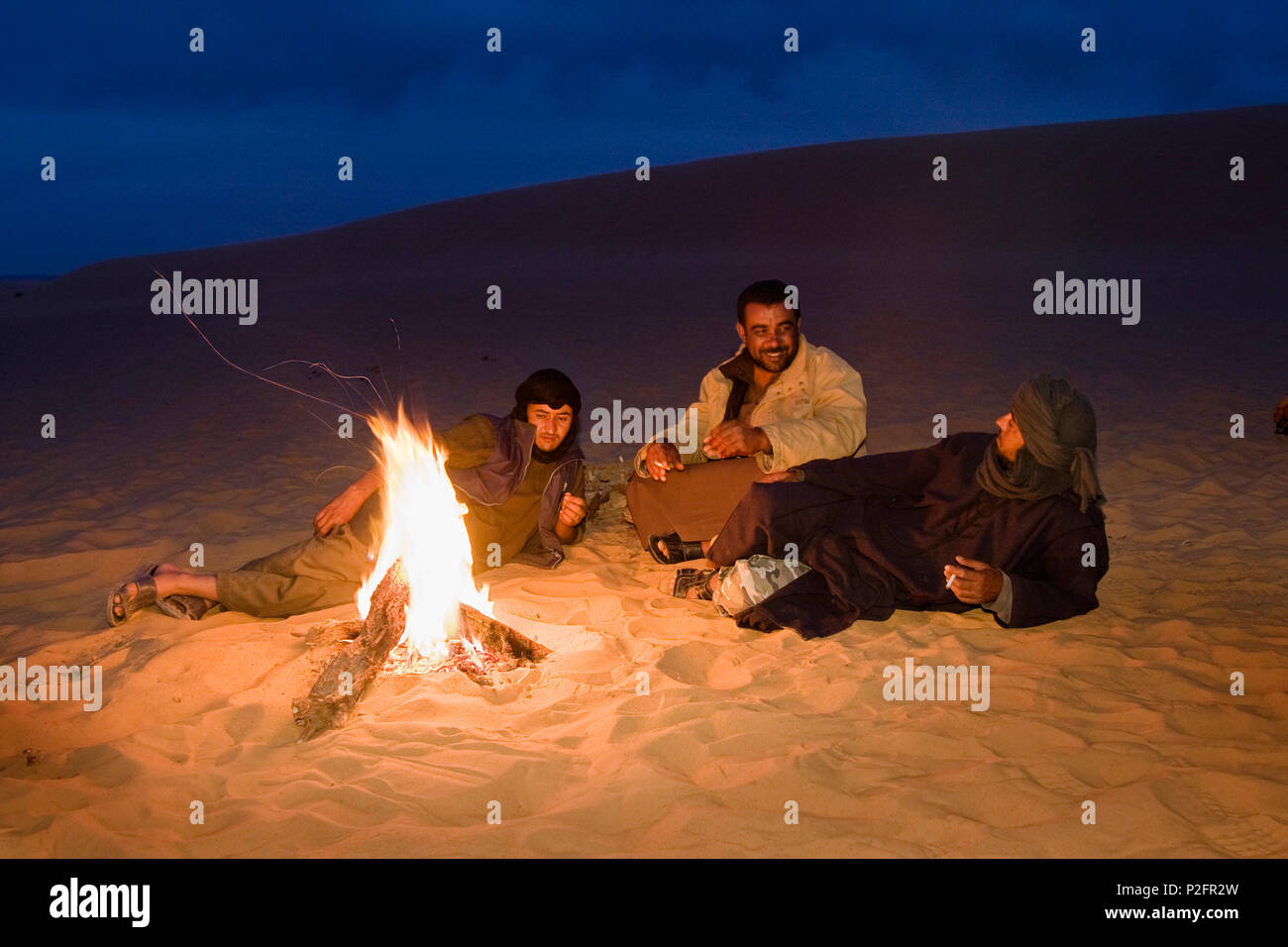 beduins warming at campfire, Akakus mountains, Libya, Africa Stock Photo