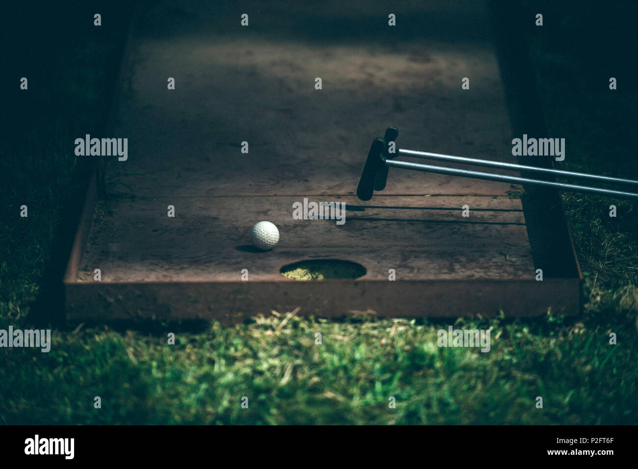 Mini golf sticks and white ball on the green grass Stock Photo