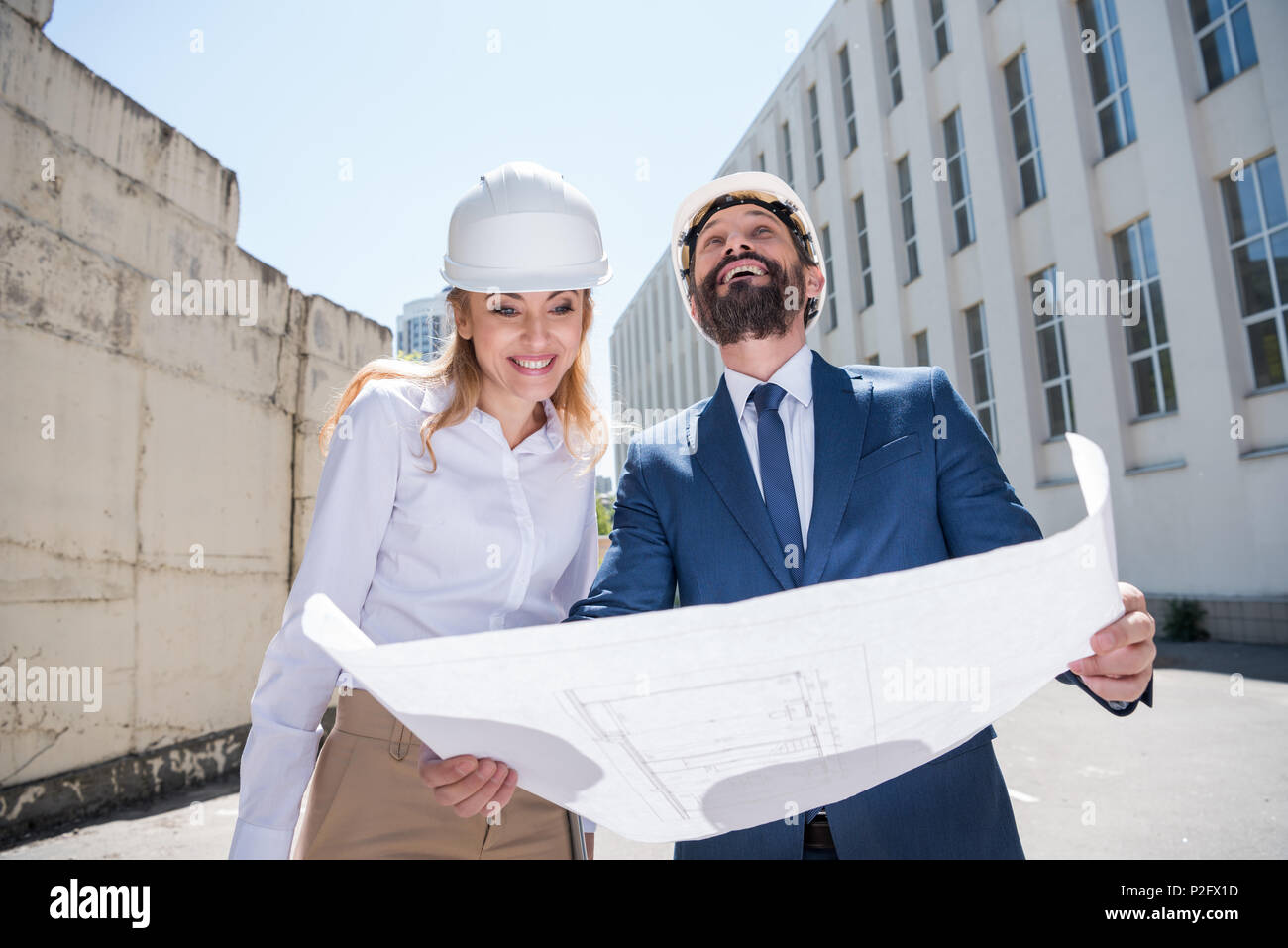Two smiling architects holding blueprint and working together Stock Photo