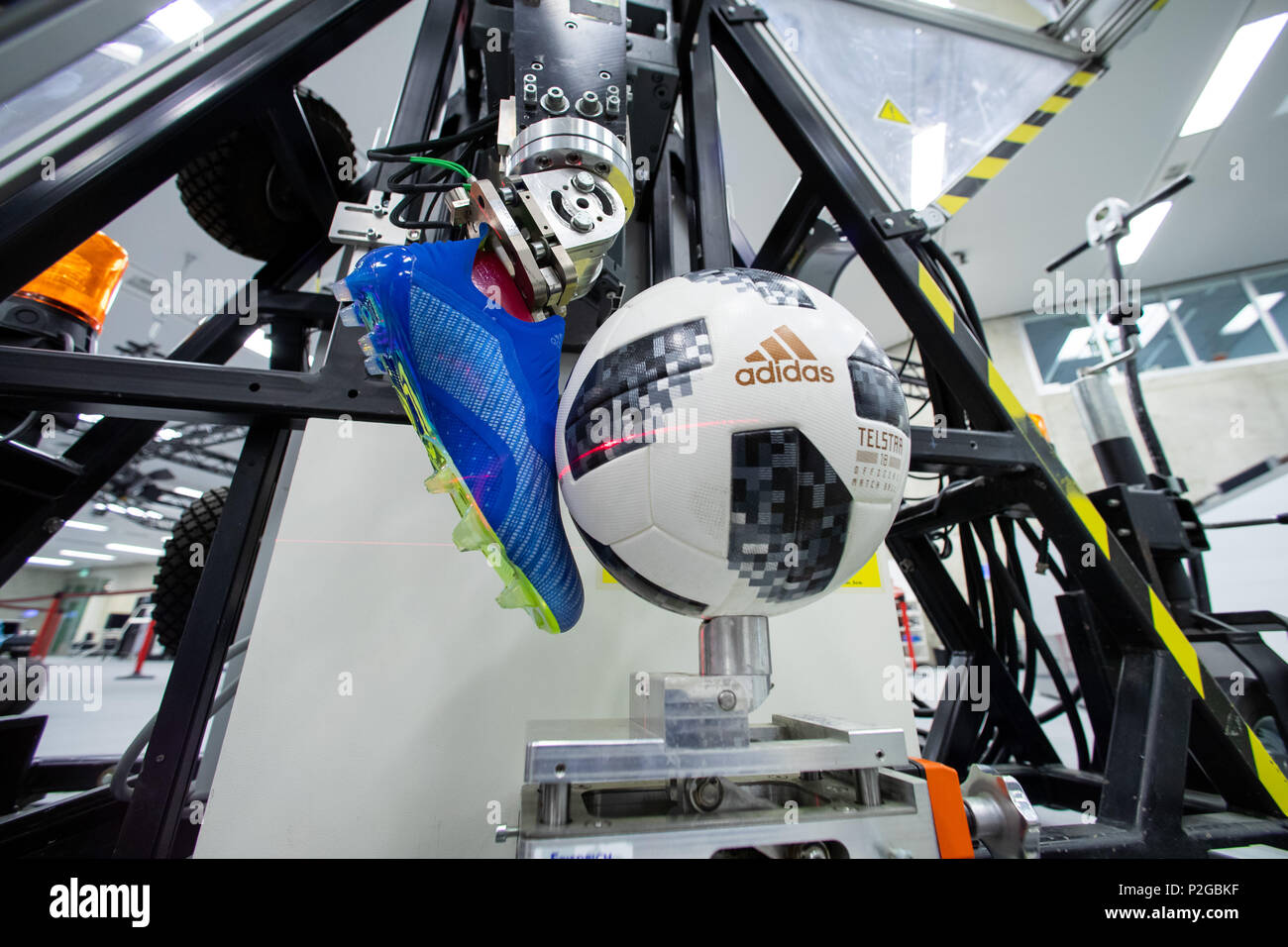 13 June 2018, Germany, Herzogenaurach: The 'Telstar 18', the official ball  of this year's FIFA World Cup in Russia, sits in front of the shoe of a  kicking robot at the research