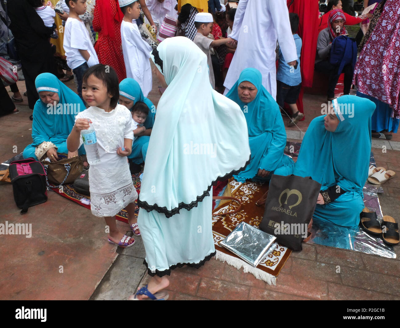 Muslim women with their daughters having a picnic after their morning prayers. Filipino and foreign Muslims gather at Quirino Grandstand in Manila to celebrate the end of Ramadan. They celebrate it with prayers, food and fun, especially for the family. Eid al-Fitr is an important religious holiday celebrated by Muslims worldwide that marks the end of Ramadan, the Islamic holy month of fasting. Stock Photo