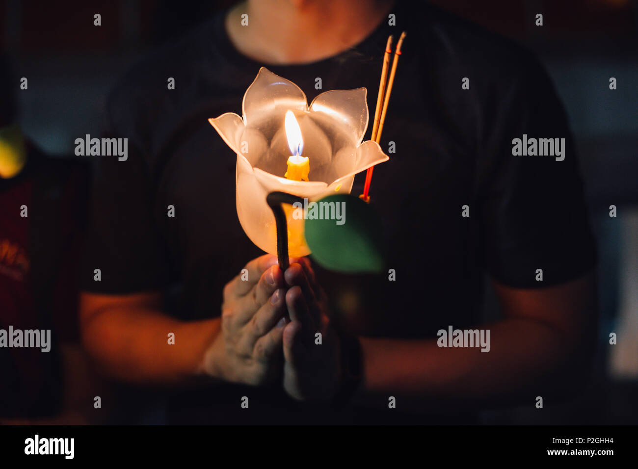 Buddhist praying with incense sticks, lotus flower and candles on holy