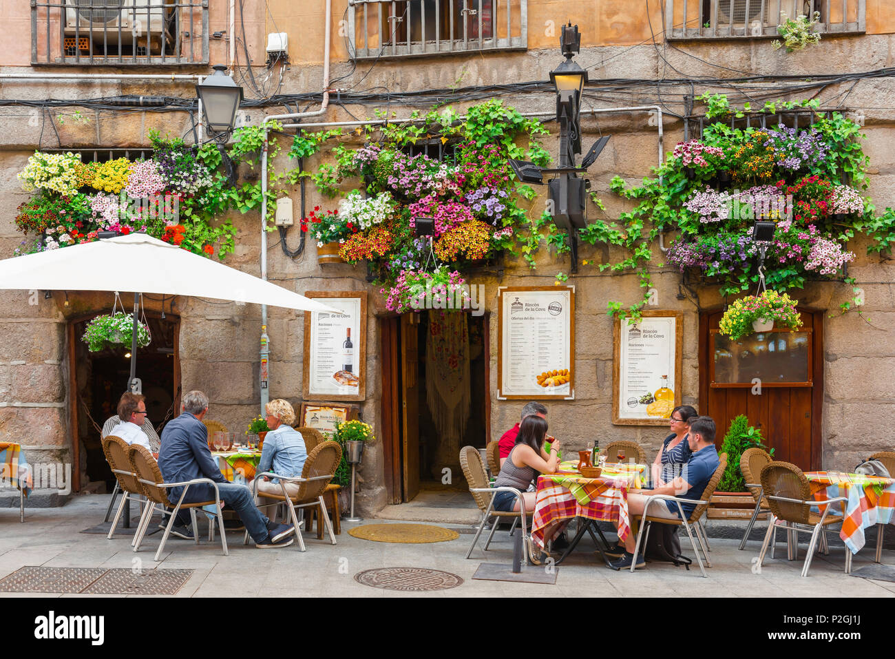Madrid street cafe, view on a summer afternoon of people relaxing at cafe tables in the historic Calle Cuchilleros old town quarter of Madrid, Spain. Stock Photo