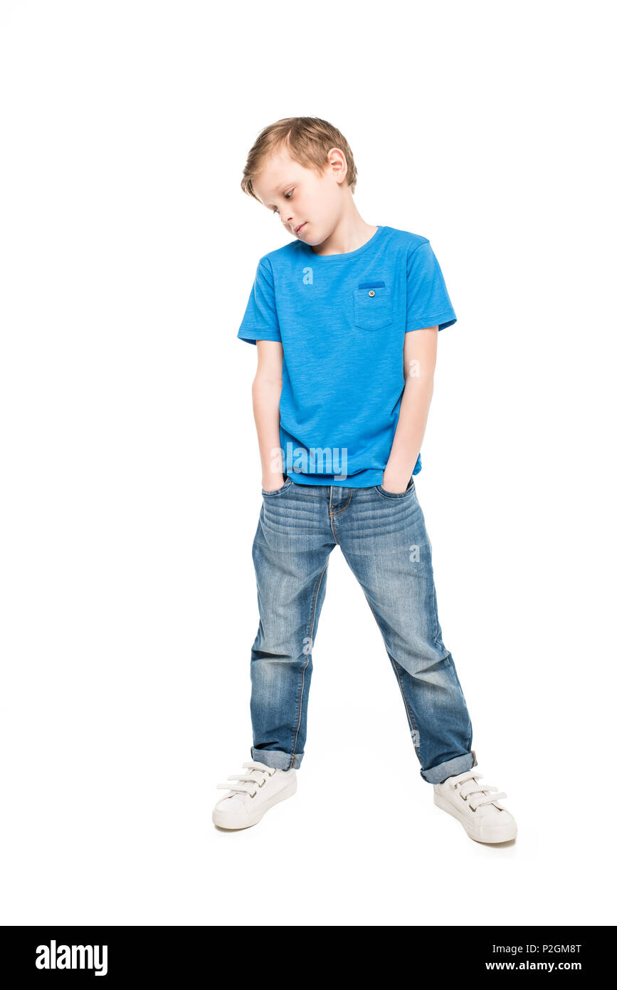 pensive little boy standing with hands in pockets and looking down