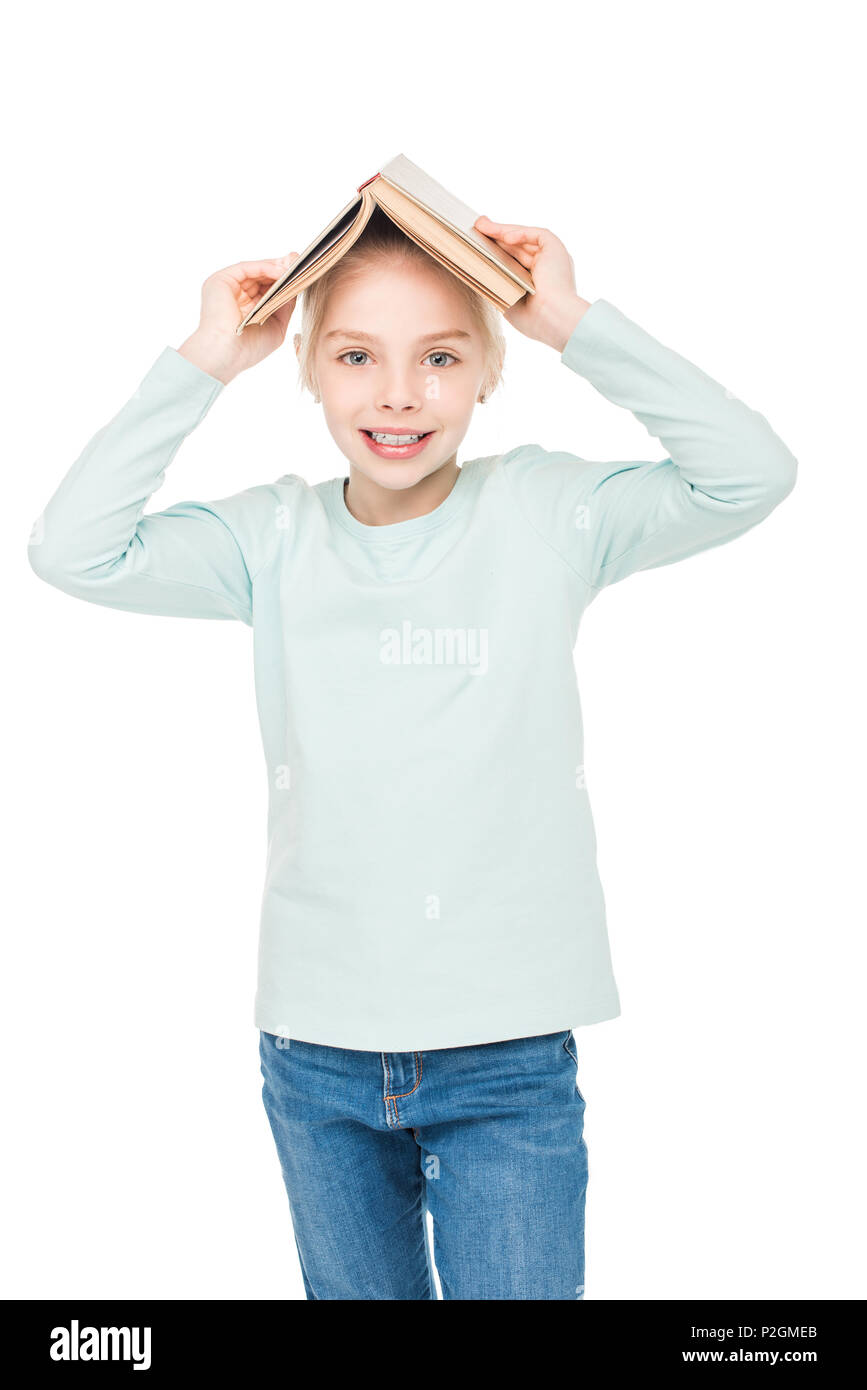 happy little girl holding open book on head and smiling at camera ...