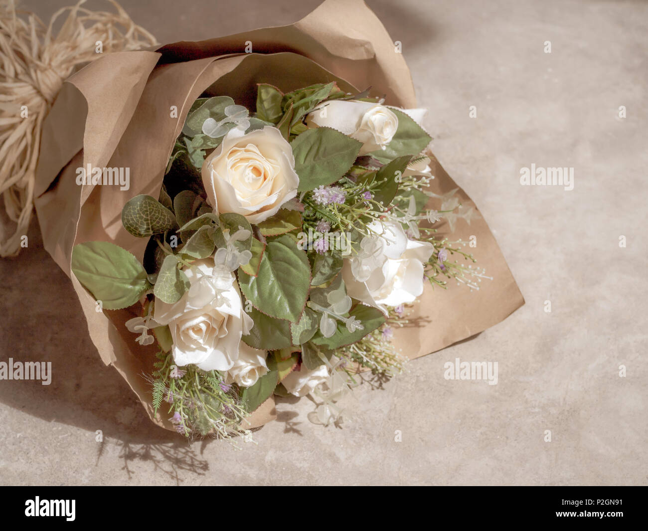 Roses and flower bouquet wrapped in kraft paper, gifting a bouquet, wrapping,  beautiful, blurry background and warm light, bouquet on table, made with  Generative AI Stock Illustration